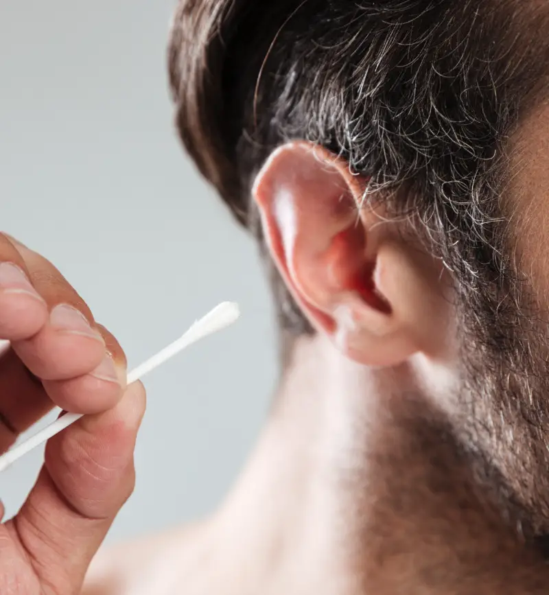 Man using cotton bud to remove earwax